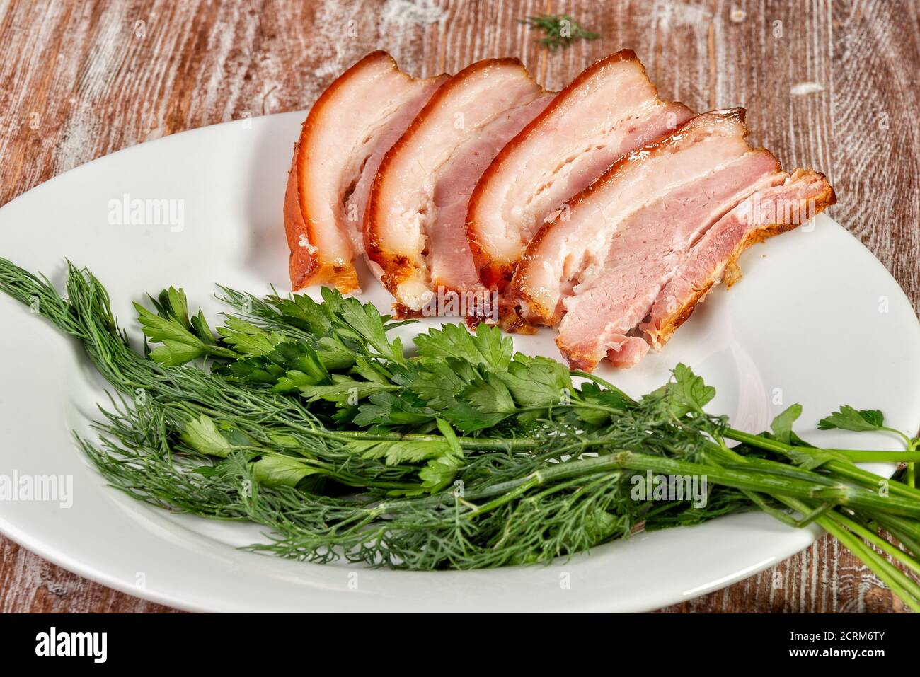 Geräuchertes Fleisch liegt mit Kräutern und Sauce auf dem Tisch Stockfoto