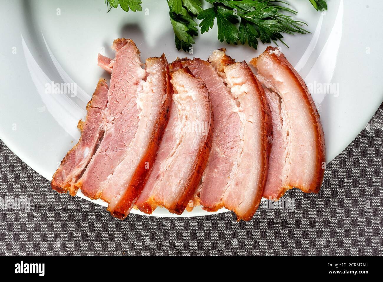 Geräuchertes Fleisch liegt mit Kräutern und Sauce auf dem Tisch Stockfoto