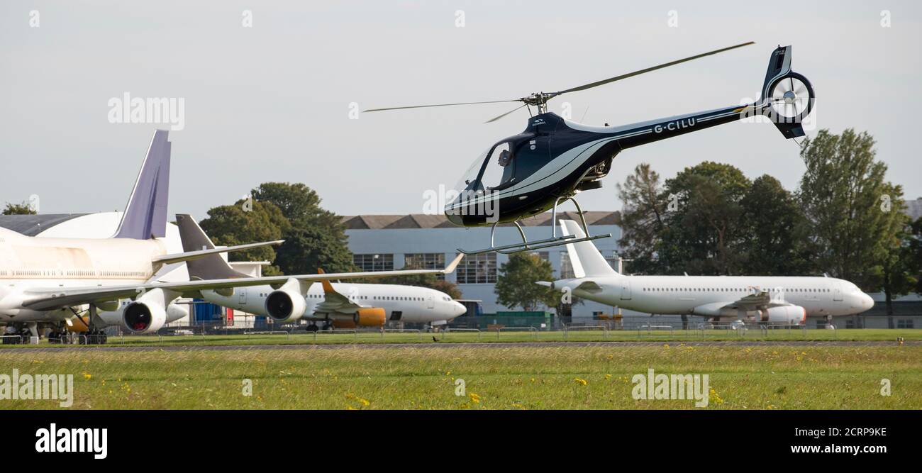 Flughafen Cotswold, Cirencester, Gloucestershire, Großbritannien. 2020. Hubschrauber fliegen in der Nähe von großen Düsenflugzeugen, die auf Verschrottung und Recycling warten Stockfoto