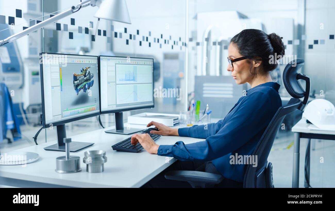 Industrieingenieurin, die Probleme löst, an einem Personal Computer arbeitet, zwei Bildschirme zeigen CAD-Software mit 3D-Prototyp der Null-Emissionen Stockfoto
