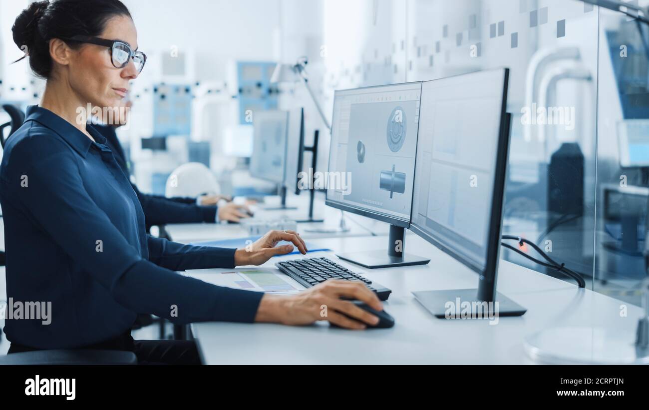 Industrieingenieur Probleme lösen, Arbeiten an einem Personal Computer, Verwenden von Maus und Tastatur, zwei Bildschirme zeigen CAD-Software mit Maschine Stockfoto