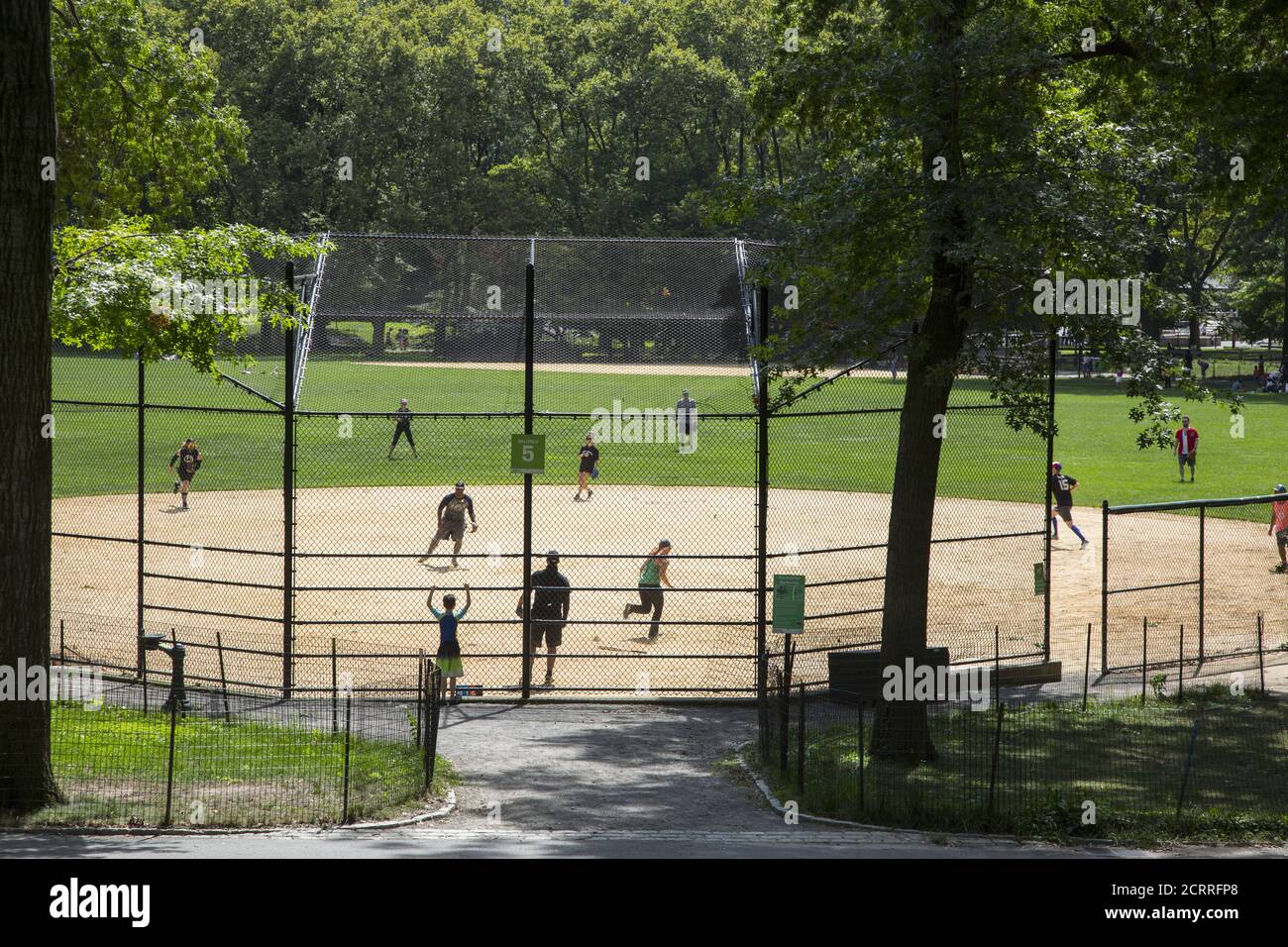 Softball Baseball-Spiel im Central Park, NYC während der Covid-19 Pandemie. Baseball hat natürliche soziale Distanzierung in das Spiel eingebaut, wo die Spieler auf dem Feld verteilt sind. Stockfoto