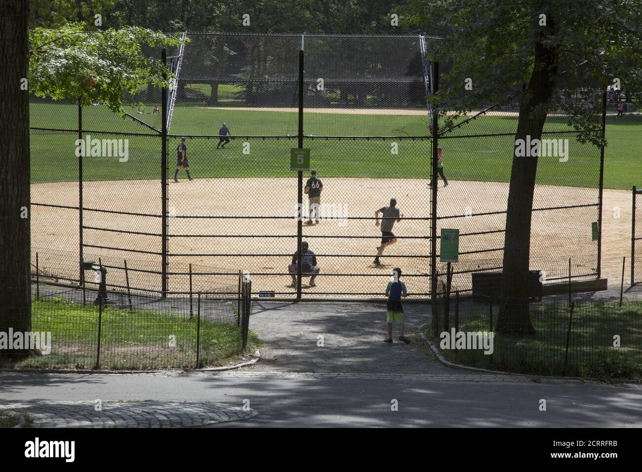 Softball Baseball-Spiel im Central Park, NYC während der Covid-19 Pandemie. Baseball hat natürliche soziale Distanzierung in das Spiel eingebaut, wo die Spieler auf dem Feld verteilt sind. Stockfoto