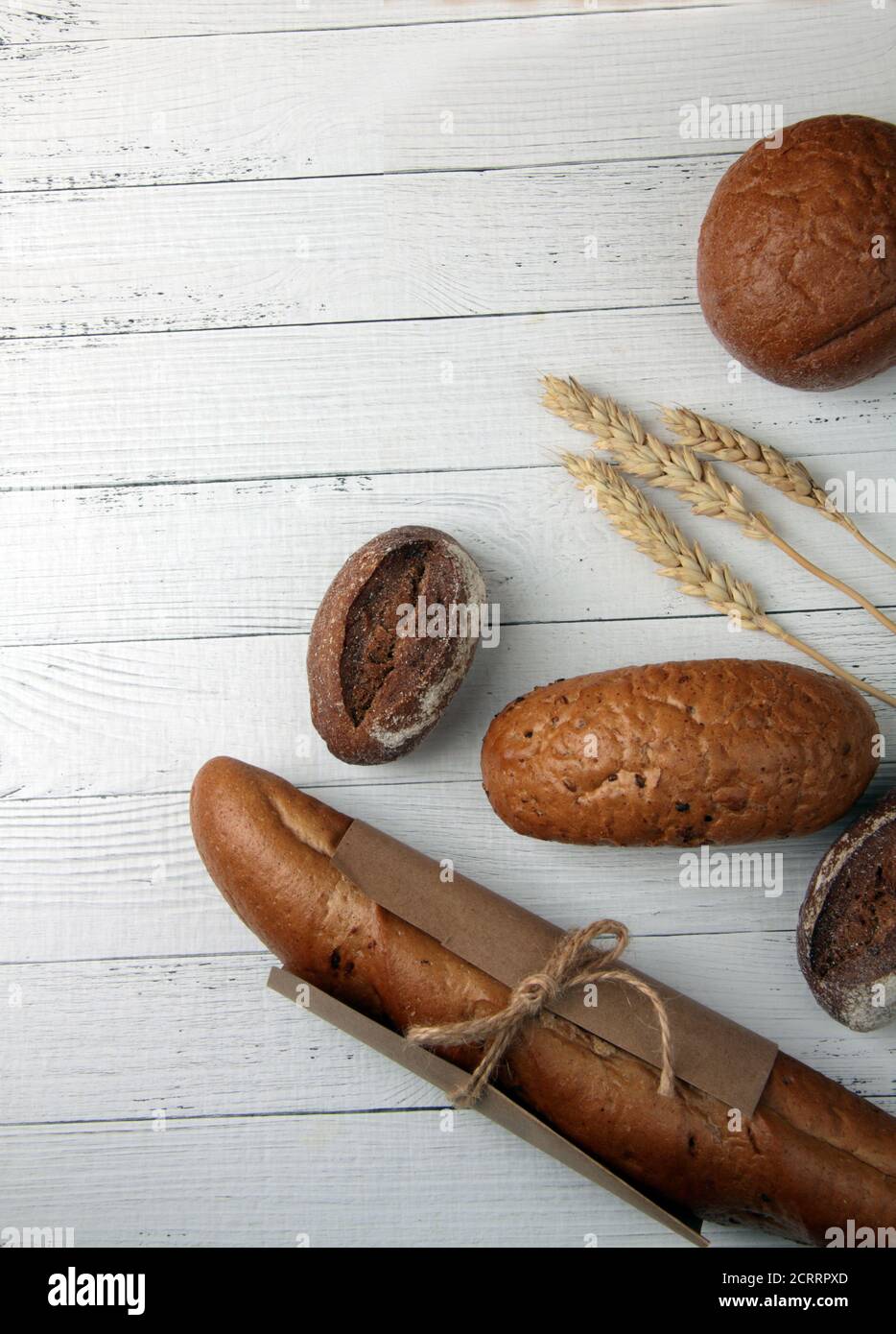 Frisches Brot - Brötchen, Baguette und Ähren von Weizen auf Holz Hintergrund flach legen. Vertikalbild. Das Bild enthält den Kopierbereich Stockfoto
