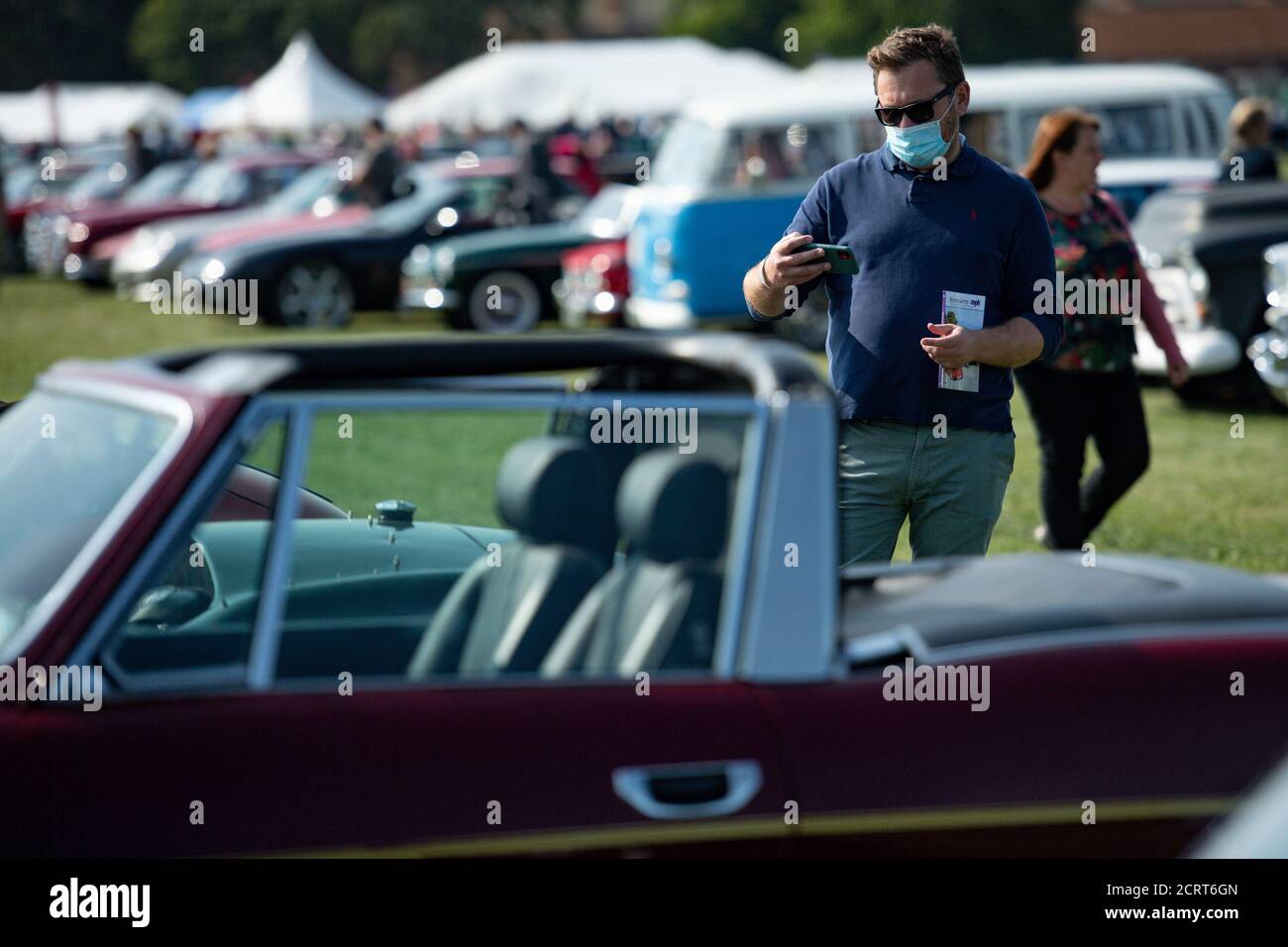 Ein Besucher mit Gesichtsmaske während der Veranstaltung Classic Car Drive in Weekend im Bicester Heritage. Stockfoto