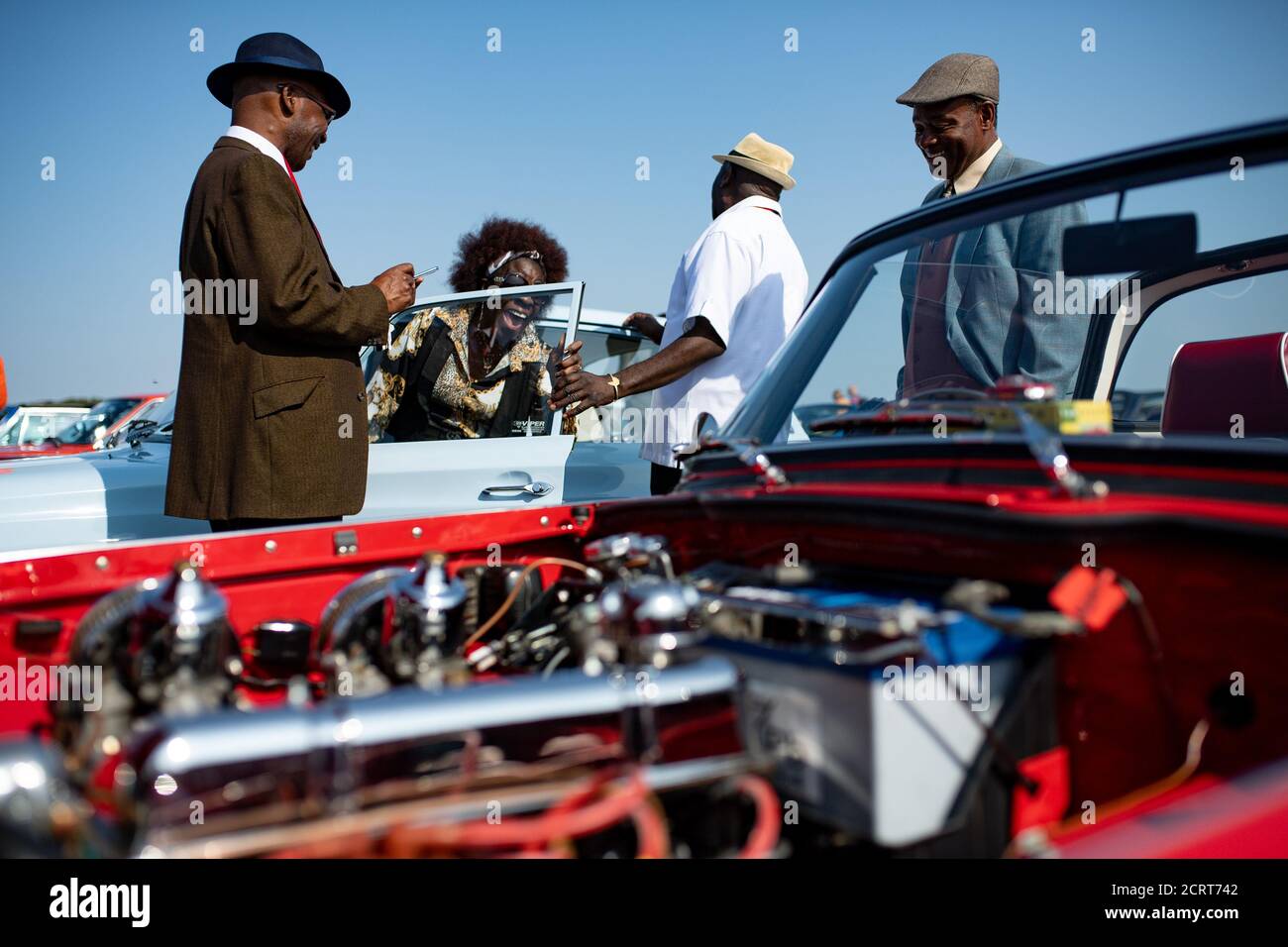 Mitglieder des Afro-Caribbean Classic and Sports Car Club während der Veranstaltung Classic Car Drive in Weekend im Bicester Heritage. Stockfoto