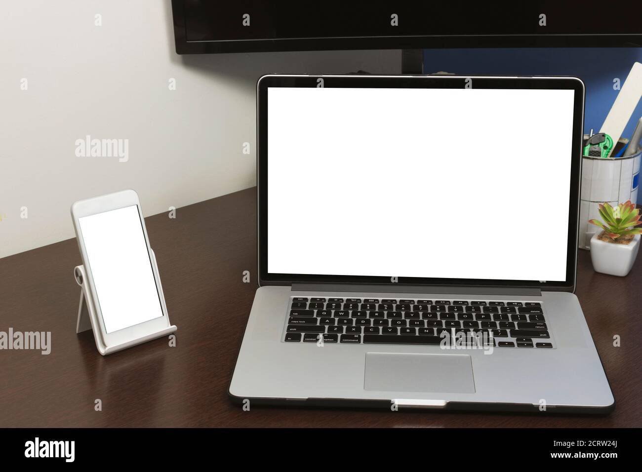 Schreibtisch Laptop und Handy mit leerem Text Bildschirm im Büro auf Holztisch. Abbildung des konzeptuellen Arbeitsbereichs eines Laptops. Stockfoto