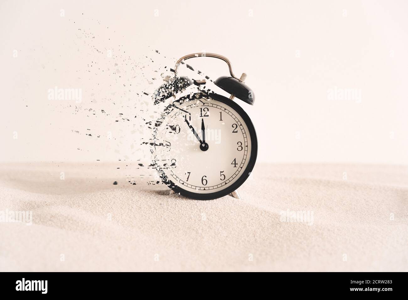 Konzept des Vergehens, die Uhr zerfällt in Stücke. Analoge Uhr im Sand, mit Dispersionseffekt. Stockfoto