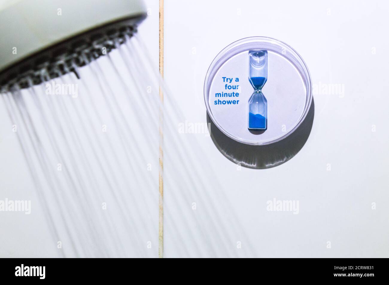 Sparen Sie Wasser vier Minuten Dusche Timer und Duschkopf mit Wasser fließt Stockfoto