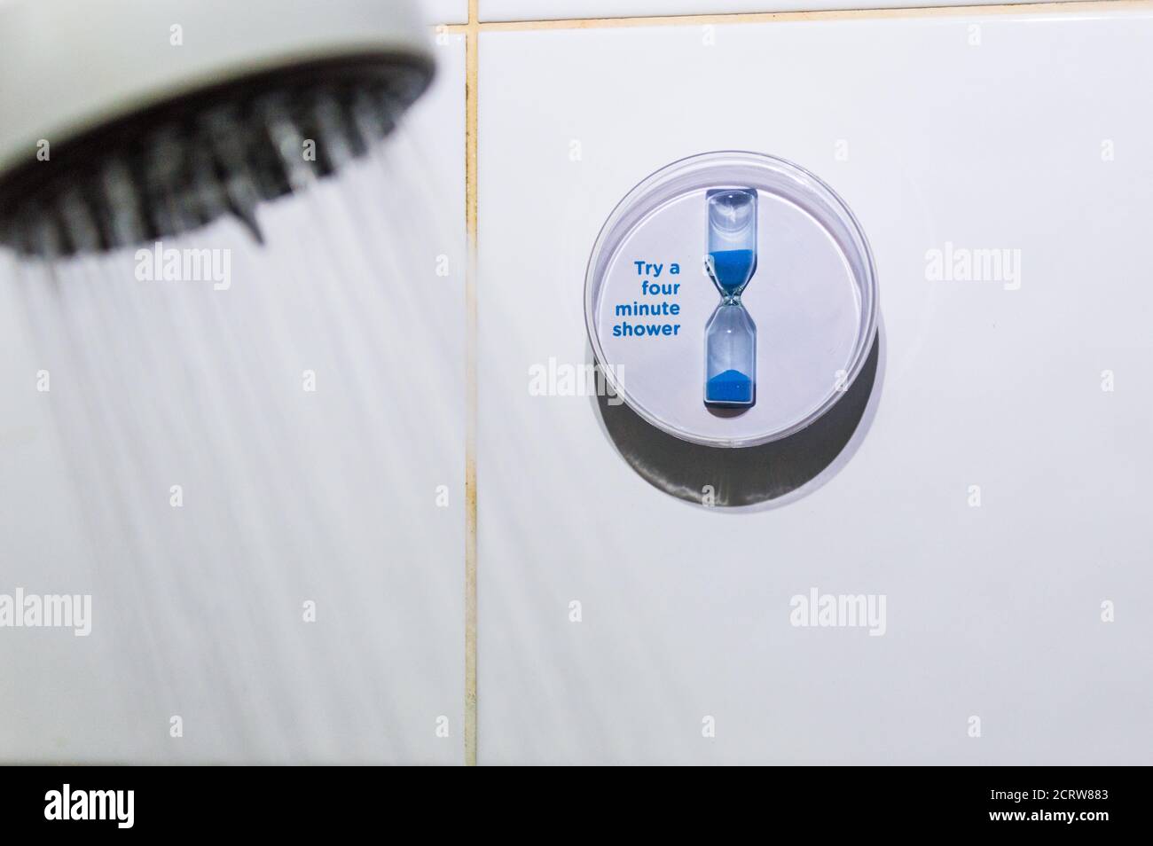 Sparen Sie Wasser vier Minuten Dusche Timer und Duschkopf mit Wasser fließt Stockfoto