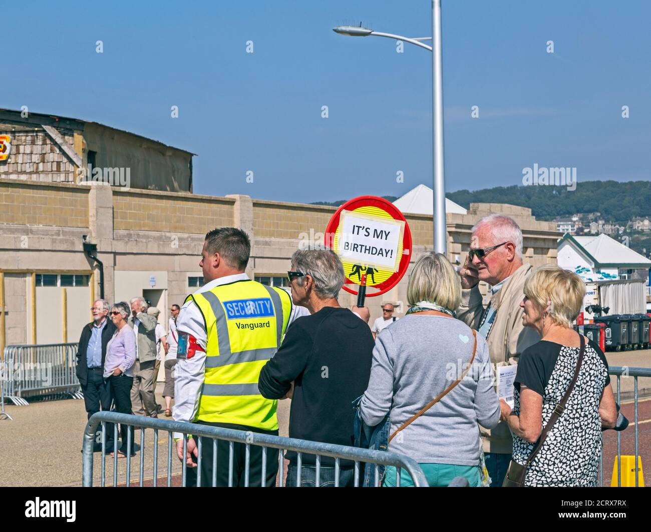 Ein sicherheitsbeamter kontrolliert den leiter der Warteschlange für den Eintritt in Dismaland, eine von Banksy kuratierte Kunstausstellung im Tropicana, einem verfemten ehemaligen lido in Weston-super-Mare, Großbritannien am 10. September 2015. Stockfoto