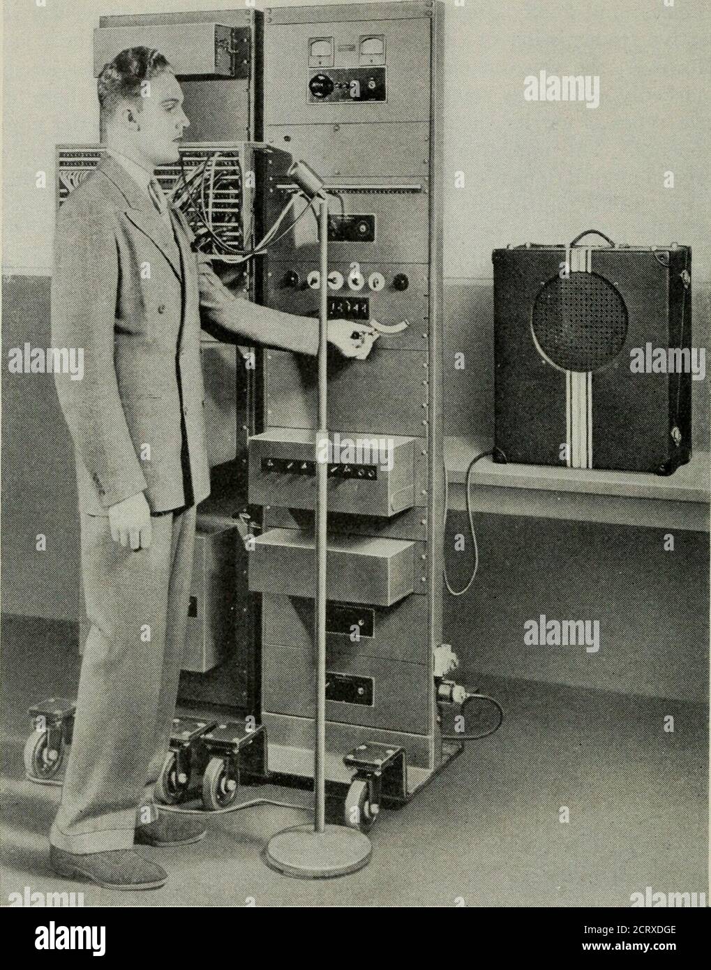 . Die technische Zeitschrift Bell System . r Demonstration ist in Abb. 4. Der voder wurde aus dem Vocoder abgeleitet, indem er manipulativ für automatische Steuerungen ersetzte. Der daraus resultierende voder, wie er auf der New York Worlds Fair gezeigt wird, ist in Abb. 5. In der Messe-Demonstration, die kontinuierlich in Abständen von etwa fünf Minuten wiederholt wird, gibt der böswillige Ansager eine einfache laufende Diskussion über die Schaltung mit dem Mädchenbediener, der auf seine Fragen antwortet, indem er Töne auf dem Voderbildet und sie in Worte und Sätze verbindet. Sie macht das, indem sie vierzehn Tasten mit ihren Fingern manipuliert, eine Stange mit ihrem lef Stockfoto