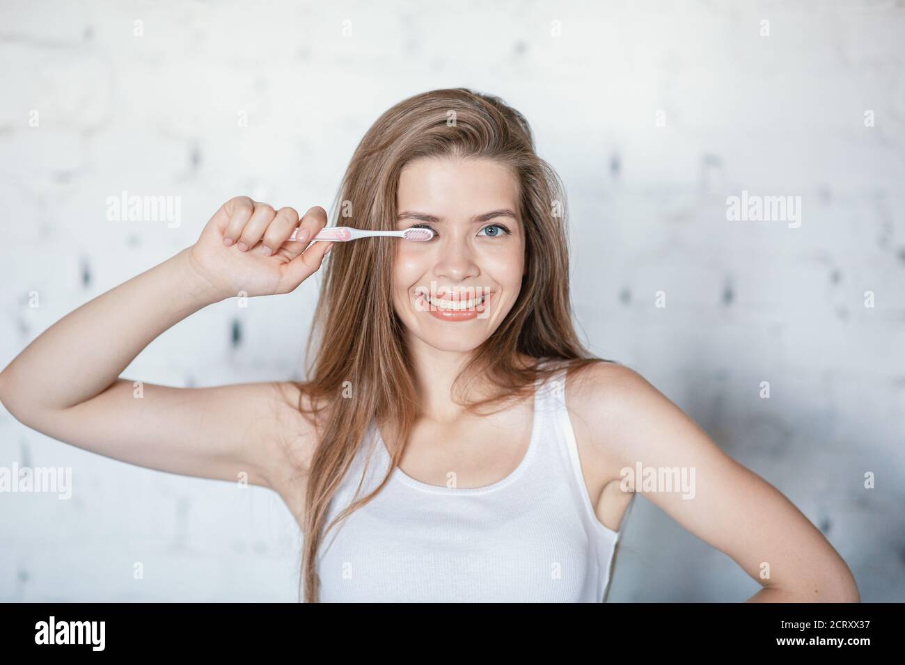 Zahnpflege. Attraktive junge Frau mit strahlendem Lächeln hält Zahnbürste drinnen Stockfoto