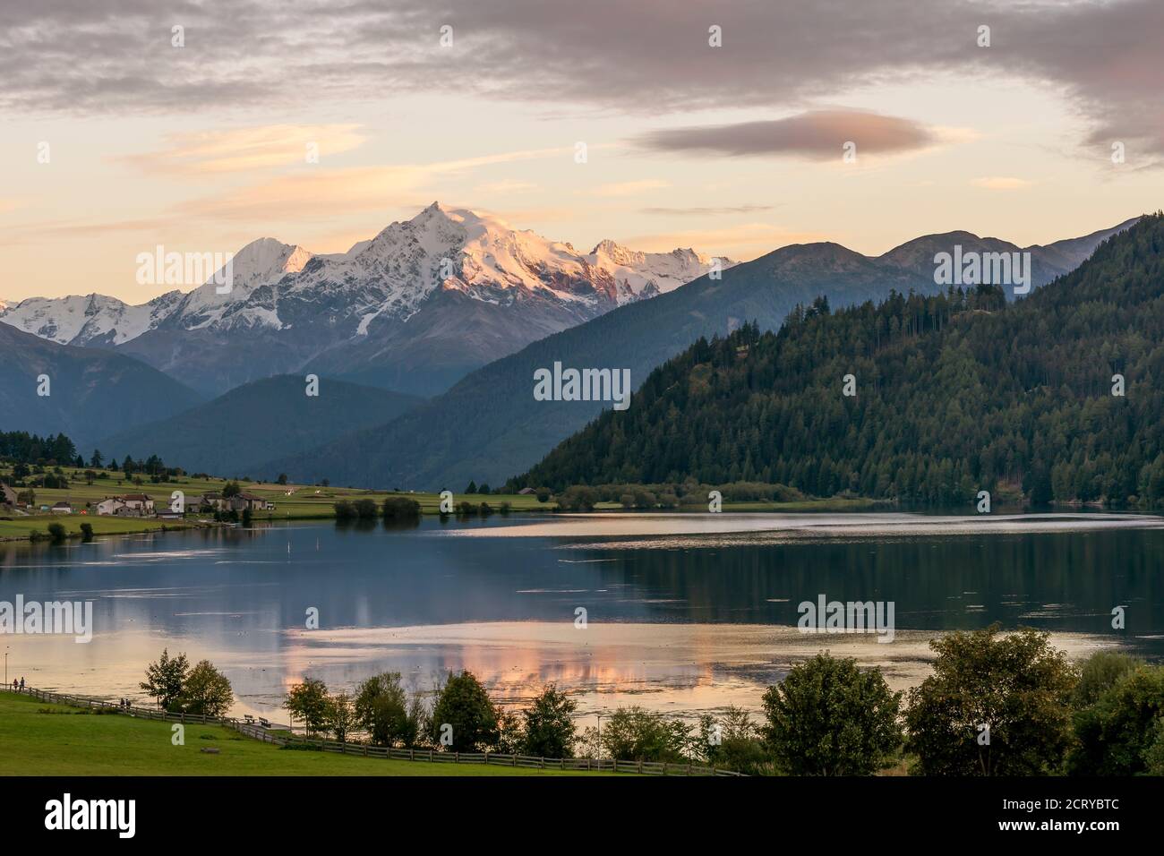 Farbenprächtiger Sonnenuntergang am Lago della Muta, mit dem verschneiten Ortler im Hintergrund, Südtirol, Italien, im Wasser reflektiert Stockfoto