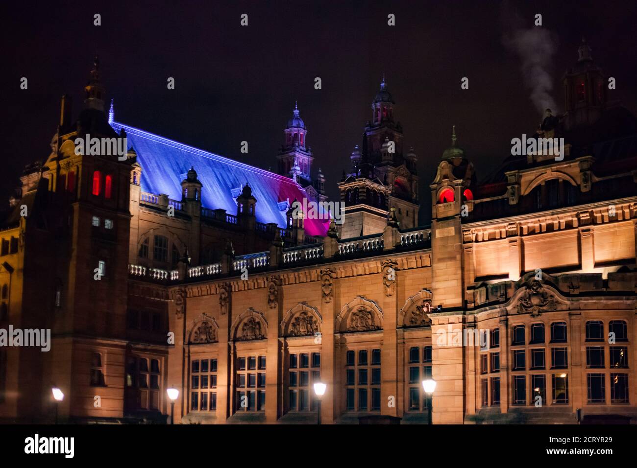 Glasgow, Schottland im Herbst. Kelvingrove Kunstgalerie und Museum bei Nacht. Farbbeleuchtung des Gebäudes. Schwarzer Nachthimmel. Stockfoto