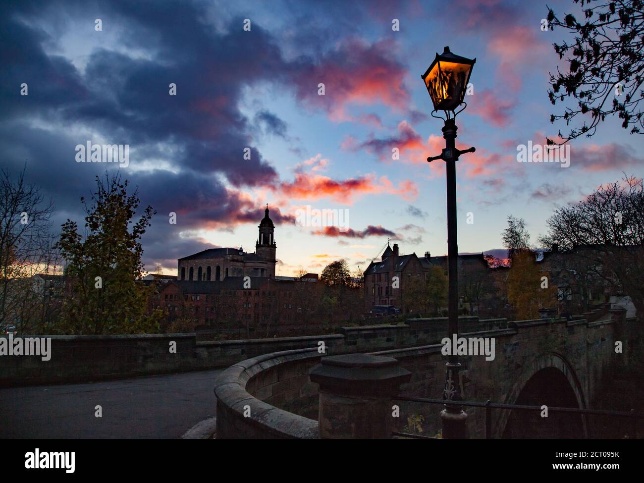 Glasgow / Schottland - 13. Nov 2013: Glasgow schöner Sonnenuntergang Stadtbild. Straßenbeleuchtung Lampe mit gelbem Licht. Evangelische Kirche im Hintergrund. Stockfoto