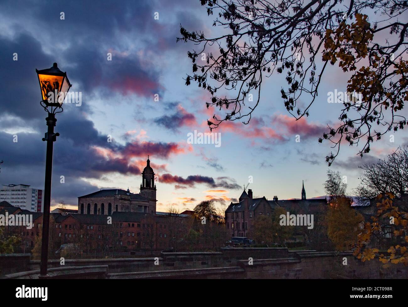 Glasgow / Schottland - 13. Nov 2013: Glasgow Stadtbild in schönem Sonnenuntergang. Straßenbeleuchtung Lampe mit gelbem Licht. Evangelische Kirche im Hintergrund. Stockfoto