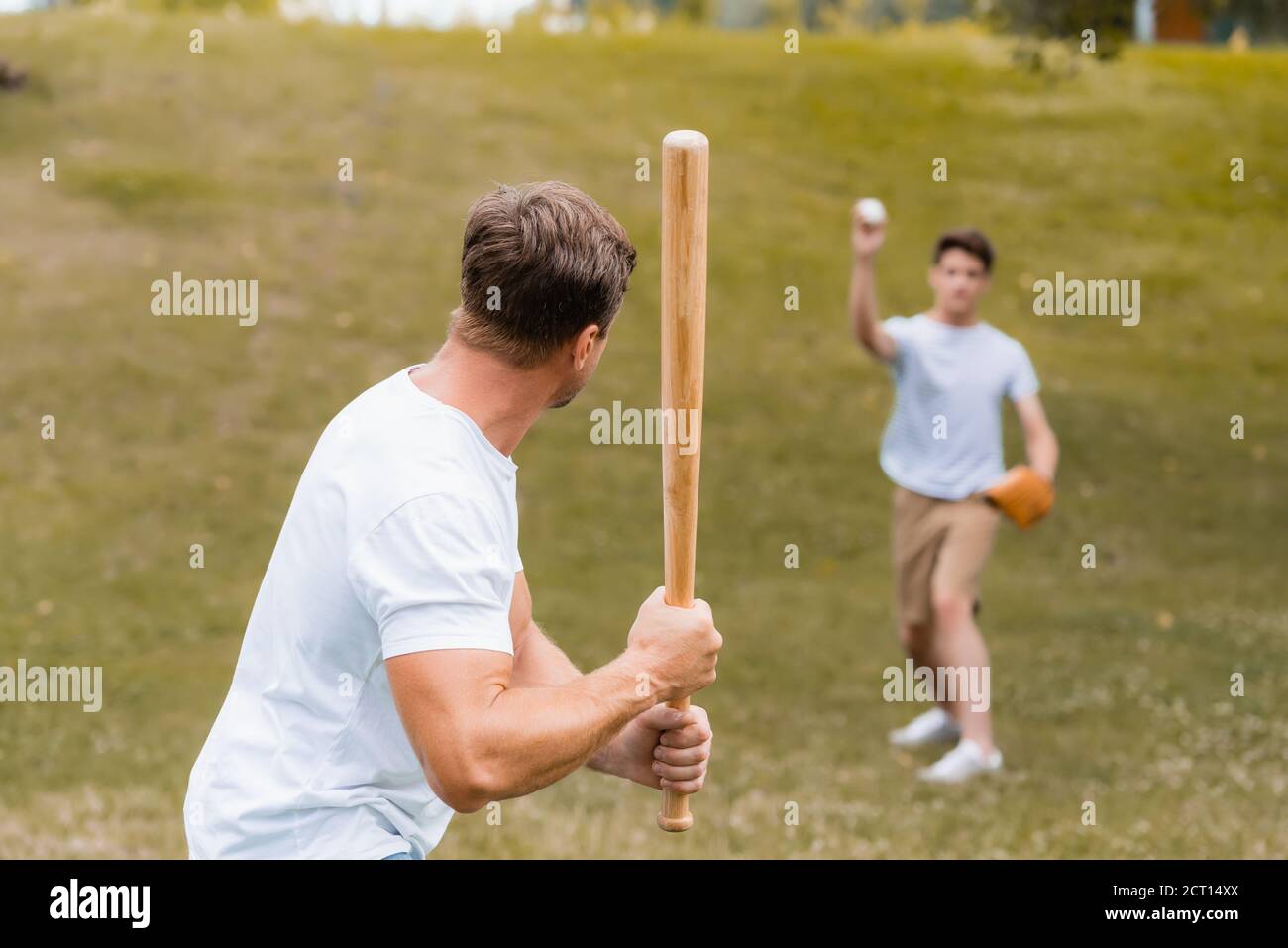 Rückansicht des Vaters hält Softballschläger während des Spiels Baseball Mit Teenager Sohn Stockfoto