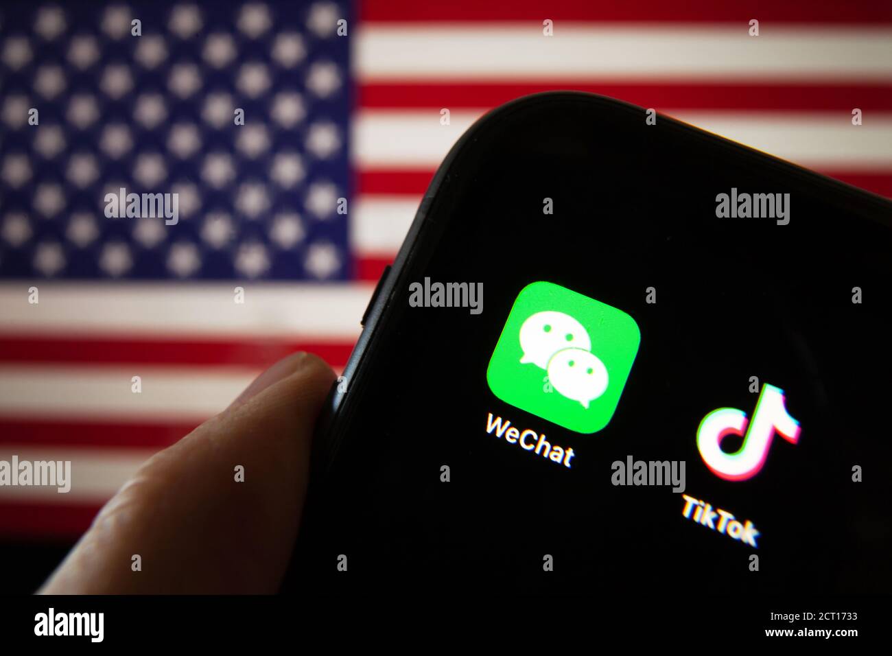 Handy mit WeChat und TikTok Icons vor der Flagge Amerikas. US-Präsident Donald Trump verbietet Apps von China aus Gründen der nationalen Sicherheit. Stockfoto