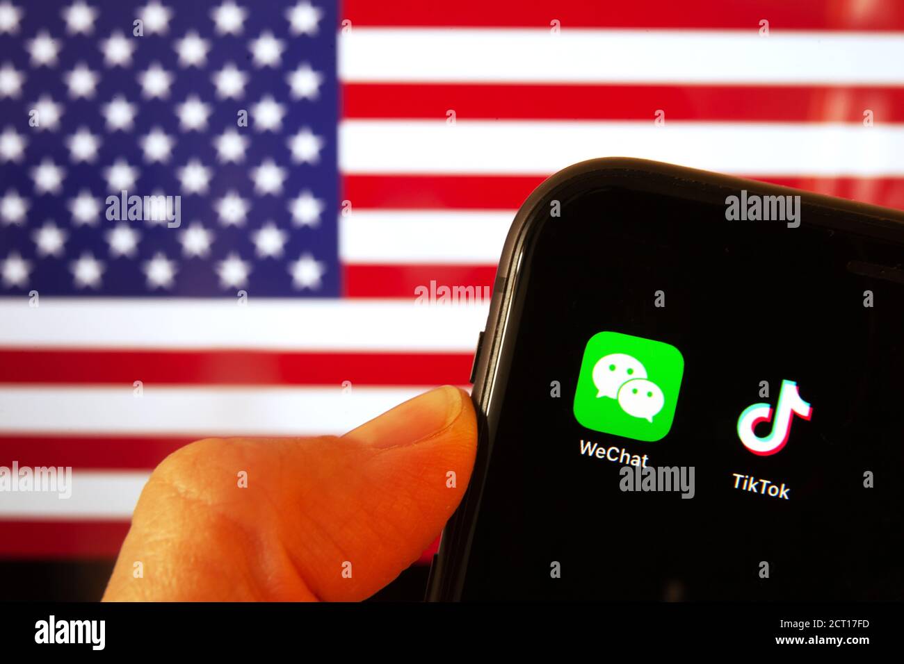 Handy mit WeChat und TikTok Icons vor der Flagge Amerikas. US-Präsident Donald Trump verbietet Apps von China aus Gründen der nationalen Sicherheit. Stockfoto