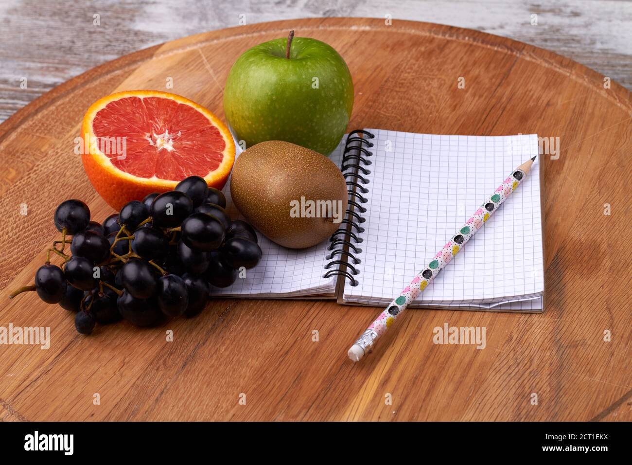 Notizblock mit Bleistift und Obst auf dem Tisch. Stockfoto
