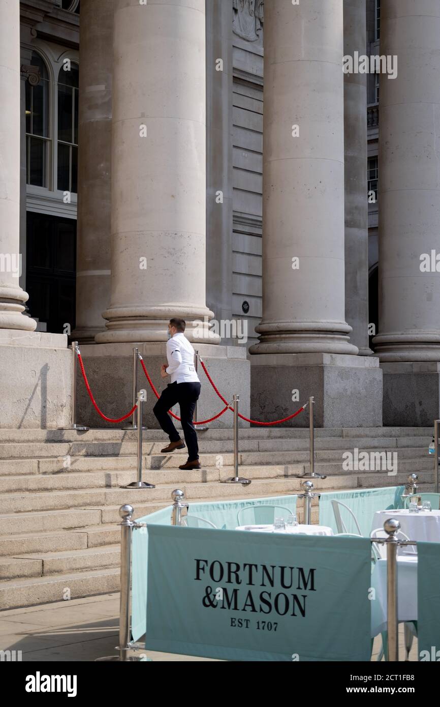 Ein Kellner läuft die Stufen der Royal Exchange hinauf, wo Fortnum & Mason während der Coronavirus-Pandemie am 9. September 2020 in London, England, ein Restaurant und eine Bar im Freien gegenüber der Bank of England in der City of London eingerichtet haben.am 16. September 2020 in London, England. Stockfoto