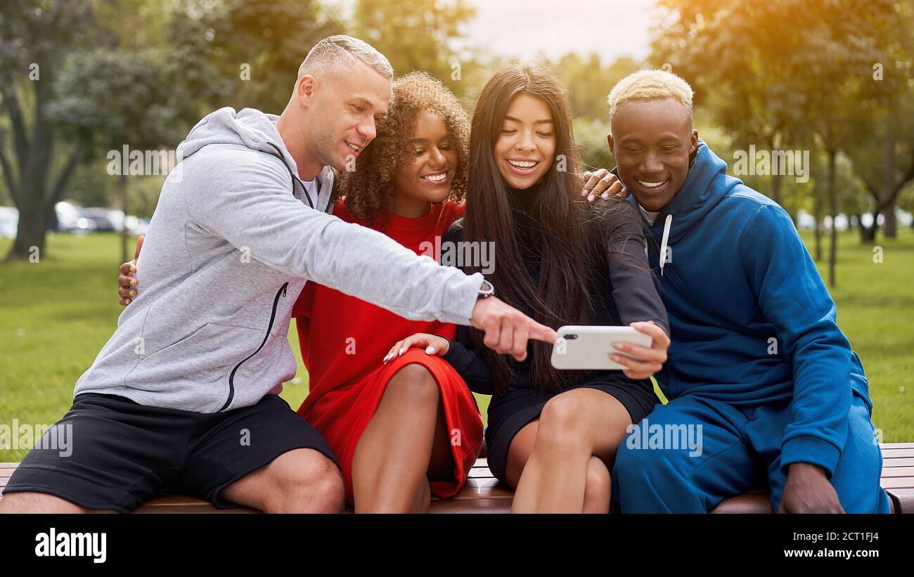 Multi ethnische Freunde im Freien suchen Smartphone-Bildschirm. Diverse Gruppe Menschen Afro american asiatisch kaukasisch verbringen Zeit zusammen multirassischen männlichen Fem Stockfoto