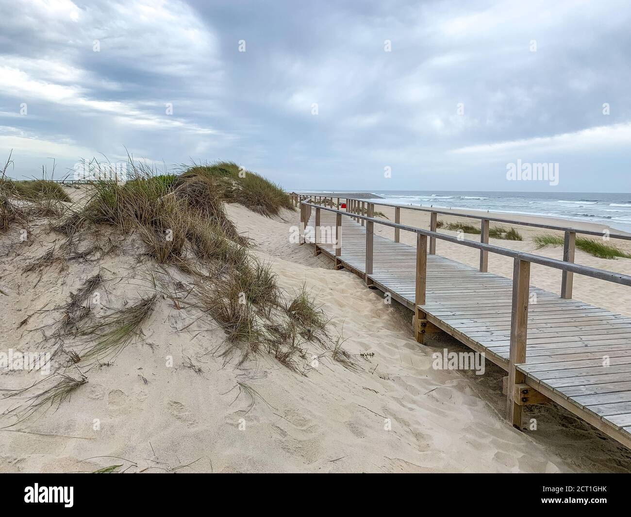 Holzboardwalk in der Nähe der Sanddünen in Costa Nova, Portugal mit dem Meer im Hintergrund Stockfoto