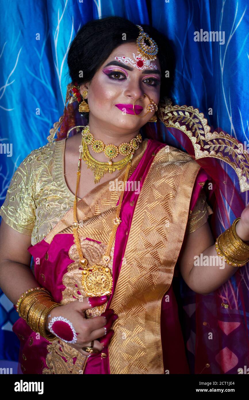 Porträt eines niedlichen indischen Modell in Braut-Look mit Schwerer Goldschmuck und roter Sari Stockfoto