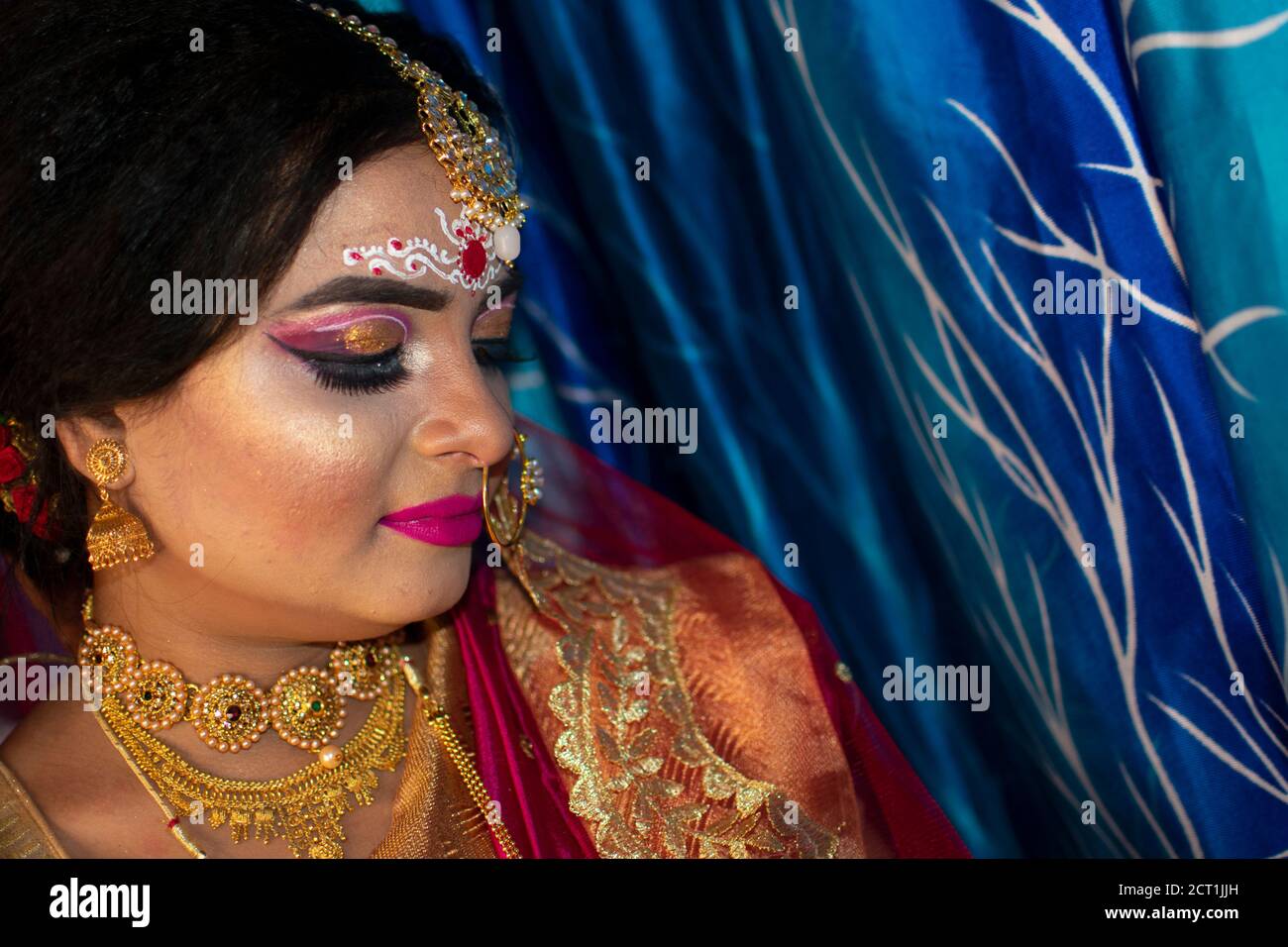 Porträt eines niedlichen indischen Modell in Braut-Look mit Schwerer Goldschmuck und roter Sari Stockfoto