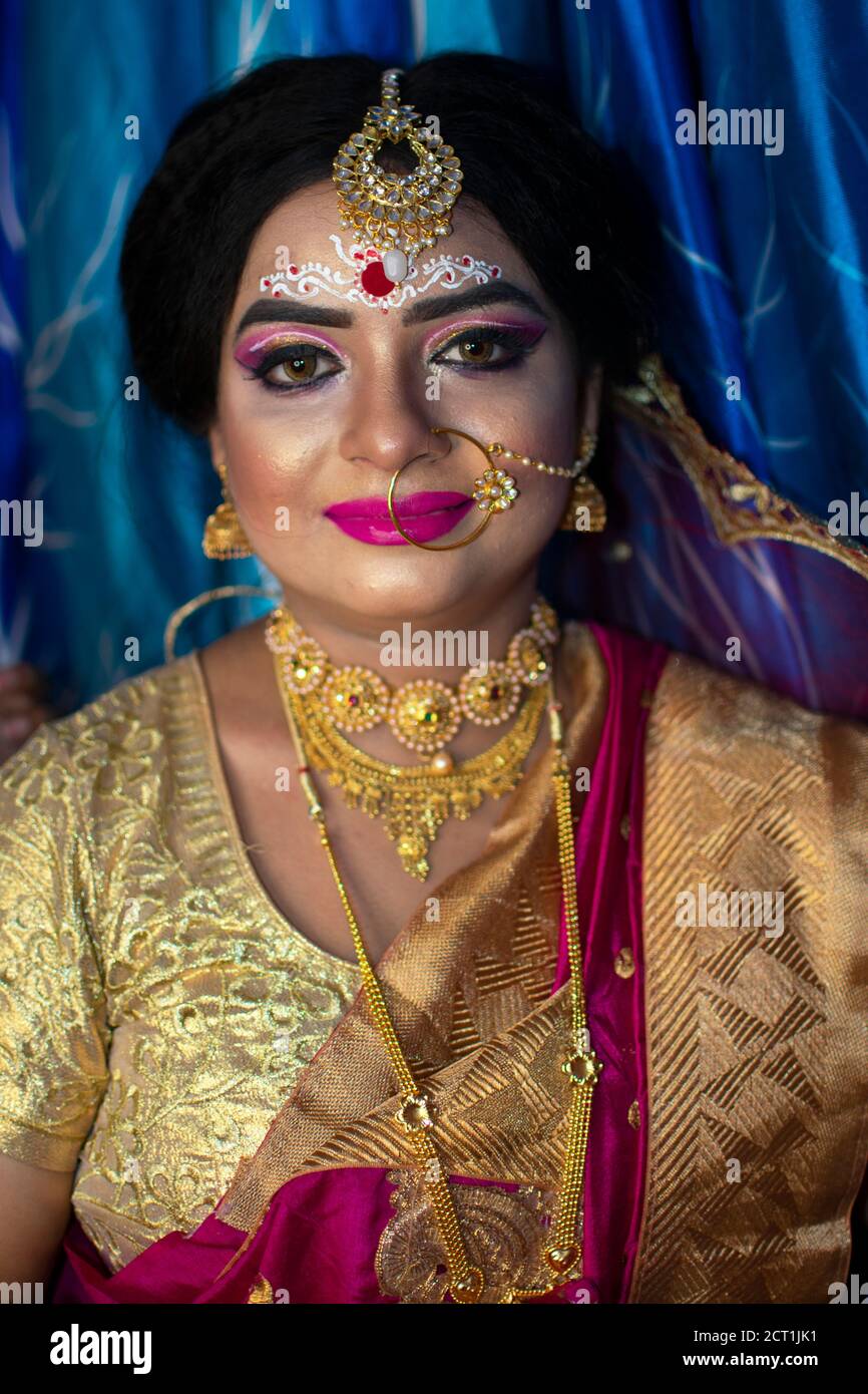 Porträt eines niedlichen indischen Modell in Braut-Look mit Schwerer Goldschmuck und roter Sari Stockfoto