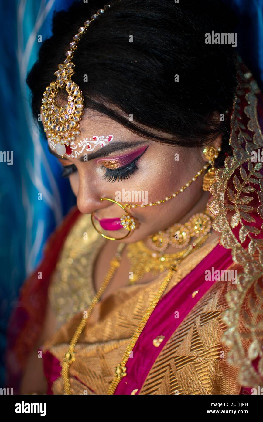 Porträt eines niedlichen indischen Modell in Braut-Look mit Schwerer Goldschmuck und roter Sari Stockfoto