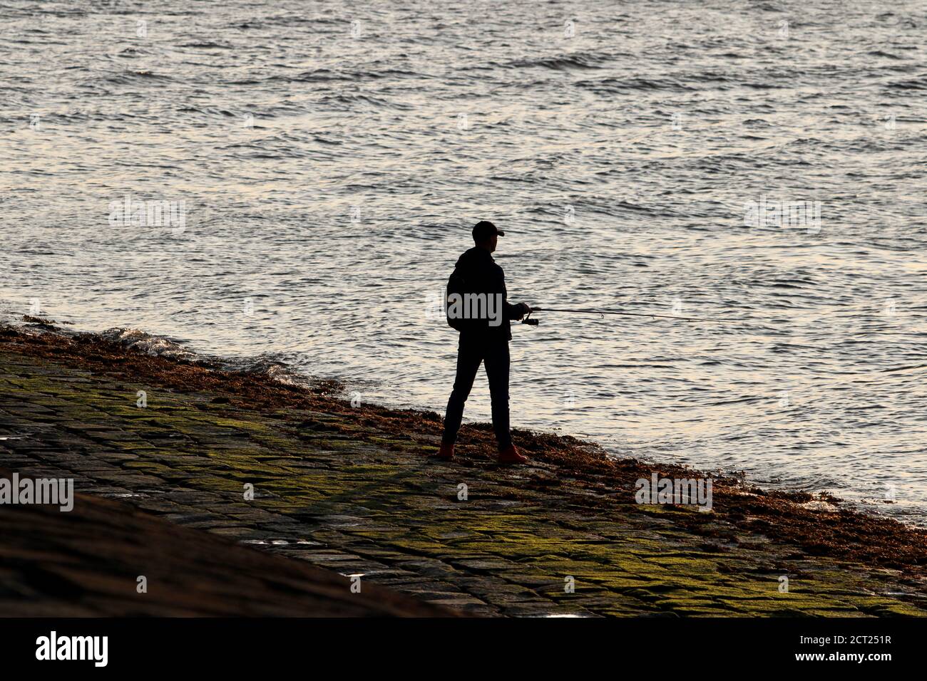 Silhouette eines Mannes, der im Firth of Forth angeln soll Bei Sonnenuntergang Stockfoto