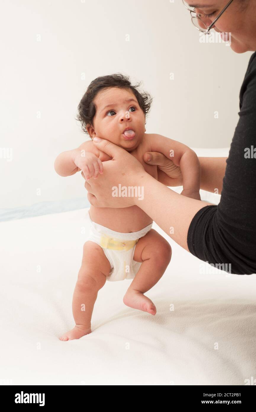 Säuglingsentwicklung Neugeborenes Mädchen im Alter von 6 Wochen aufrecht gehalten Durch Mutter Reflex treten Stockfoto