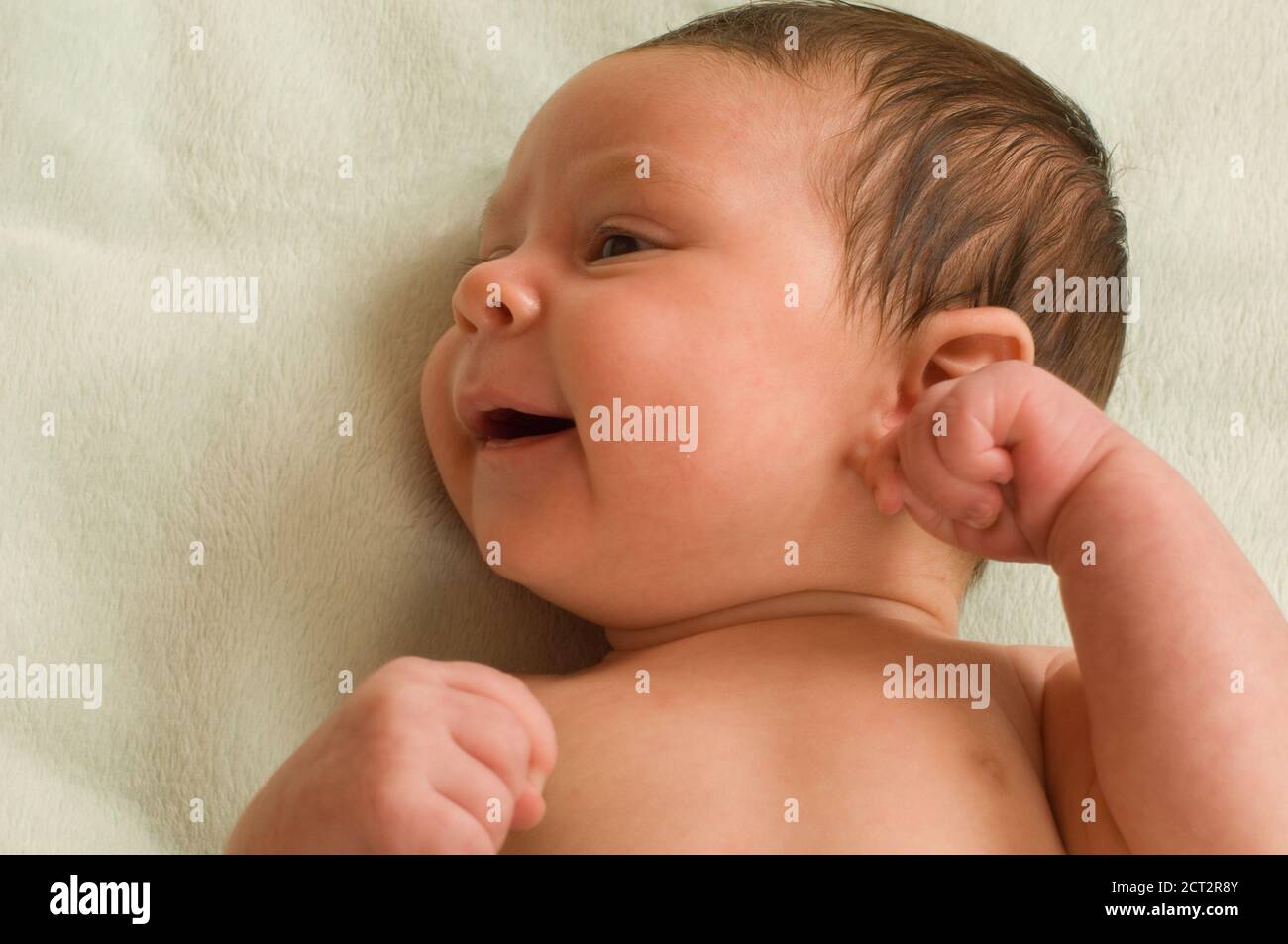 Nahaufnahme eines lächelnden neugeborenen Mädchens, ein Monat alt, der zur Seite schaut Stockfoto
