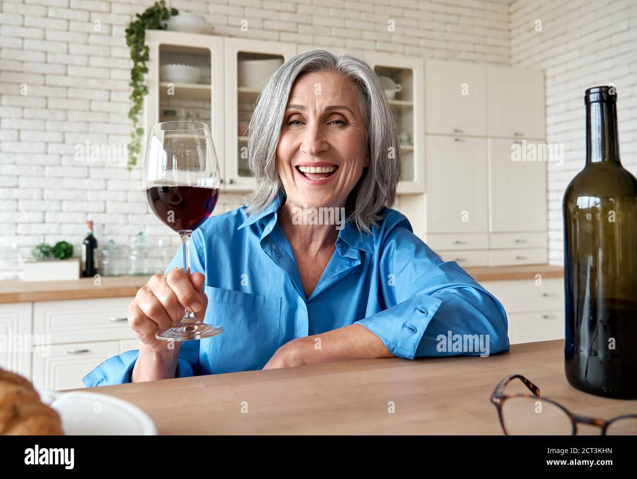 Glücklich reife Frau trinken Wein Video anrufen Freund zu Hause, Web-Kamera anzeigen. Stockfoto