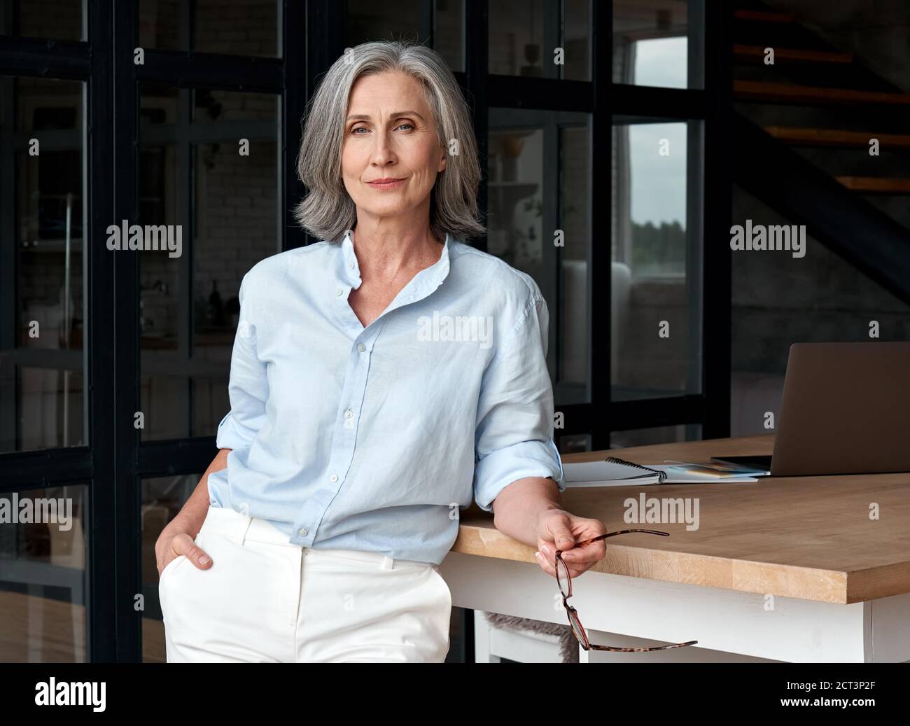 Selbstbewusst stilvolle Frau mittleren Alters am Büroarbeitsplatz, Porträt. Stockfoto