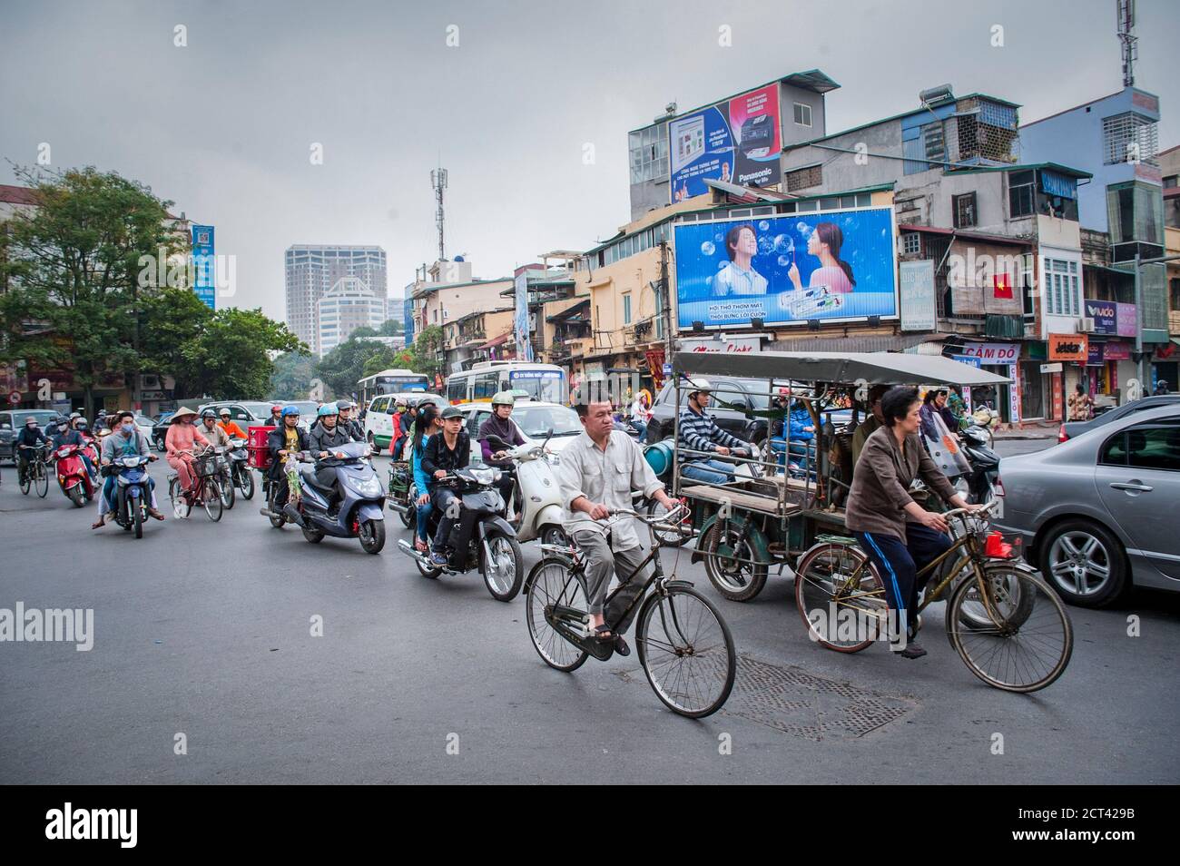 Fahrräder, Mopeds und Tuktuks fahren in den belebten Straßen von Hanoi, Vietnam, Südostasien Stockfoto
