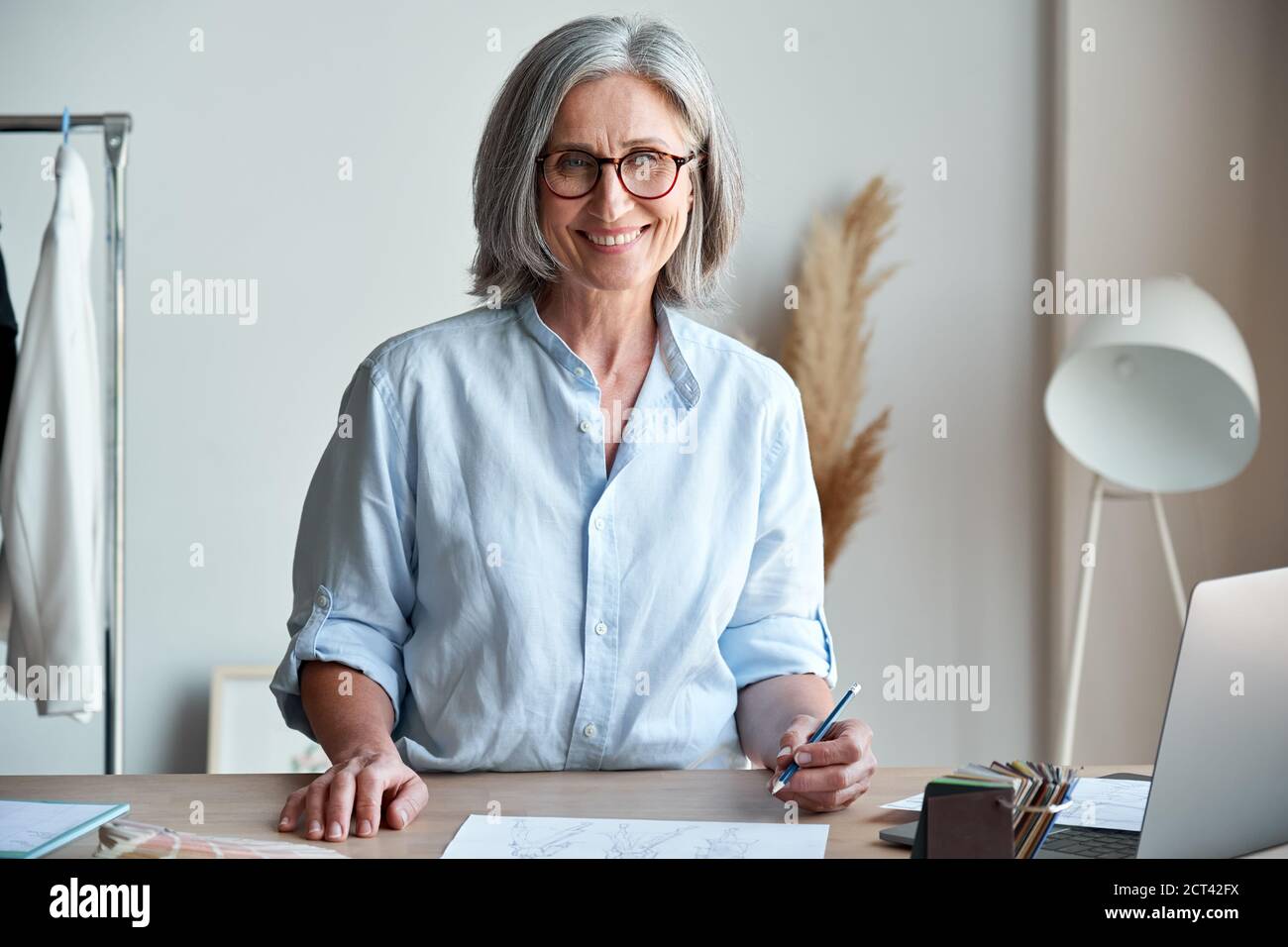 Glücklich mittleren Alters stilvolle Frau Modedesignerin am Arbeitsplatz, Porträt. Stockfoto