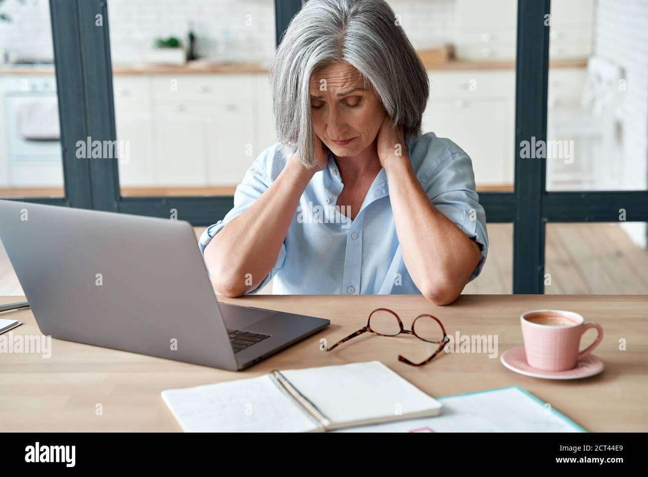 Müde gestresste alte Geschäftsfrau mittleren Alters, die unter Nackenschmerzen leidet. Stockfoto