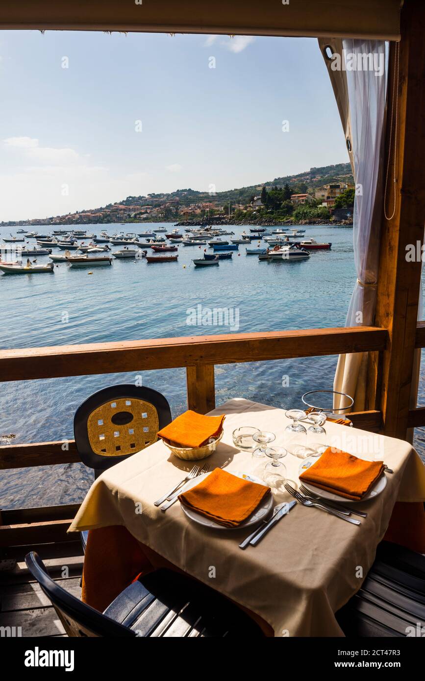 Cafe am Mittelmeer, mit Booten im Hafen von Aci Trezza, etwas außerhalb von Catania, Sizilien, Italien, Europa Stockfoto