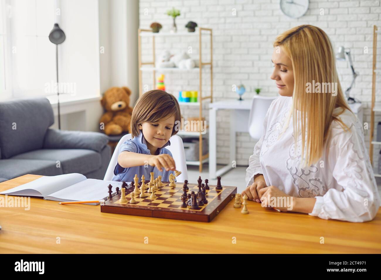 Mutter und Sohn spielen Schach am Tisch zu Hause.glücklich Familie mit Eltern und Kind genießen Brettspiel zu Hause Stockfoto