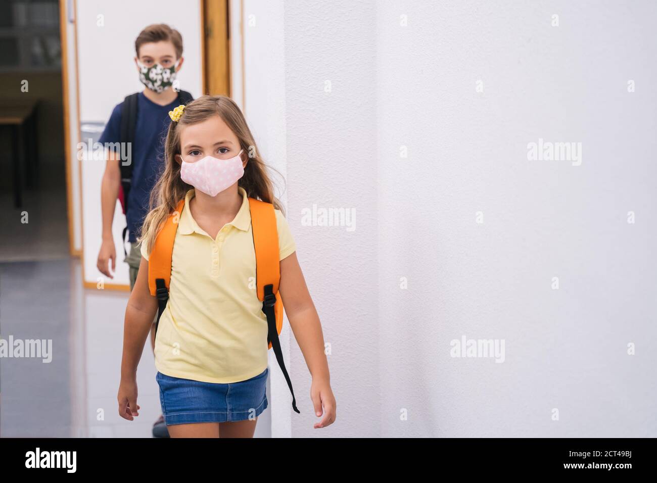 Kinder zurück zur Schule mit Maske Aufrechterhaltung sozialer Distanz während covid. Stockfoto