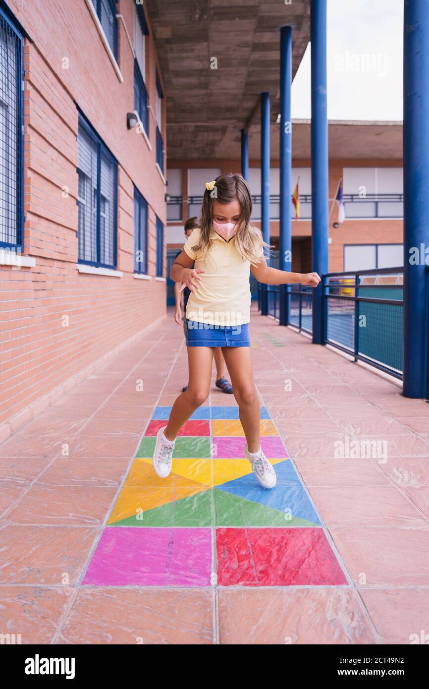 Zurück zur Schule. Kinder laufen und springen auf dem Schulhof mit Gesichtsmaske Stockfoto