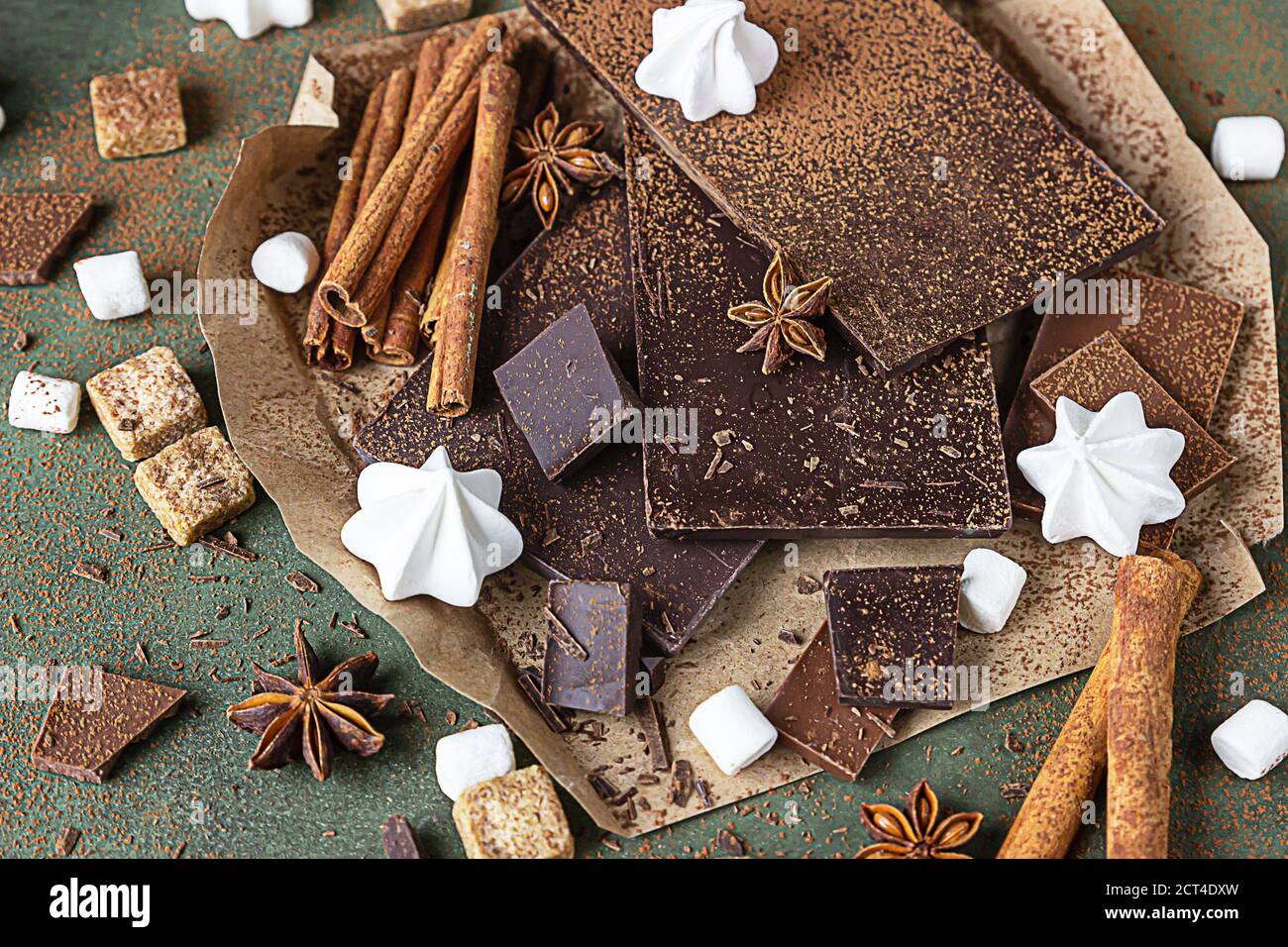 Dunkle und milchige Schokoriegel, Gewürze, brauner Zucker, Baiser und Marshmallow auf betontem Hintergrund. Sweet Food Foto Konzept. Stockfoto