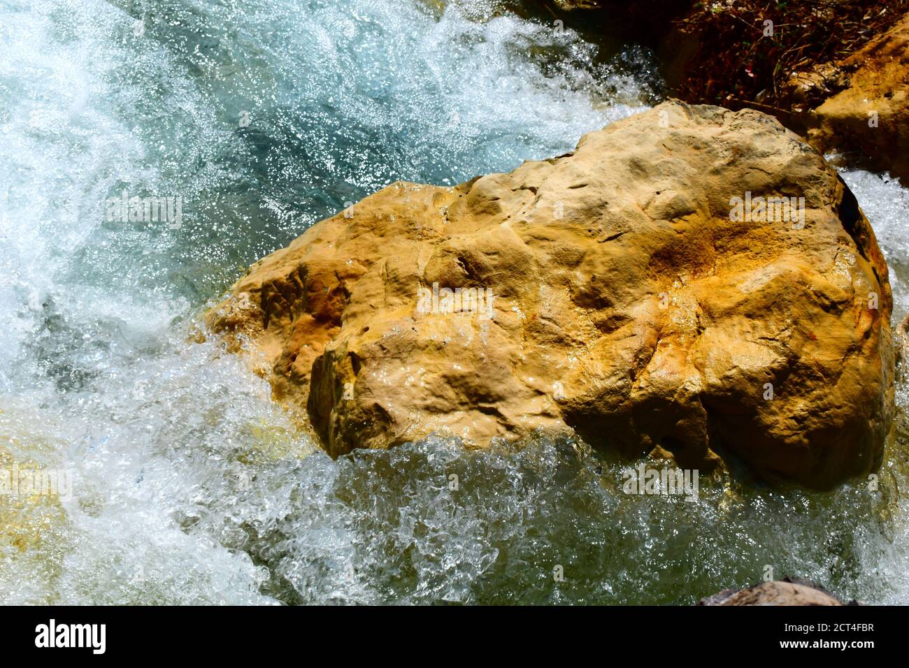 Brauner Stein, umgeben von spritzerem Wasser. Stockfoto