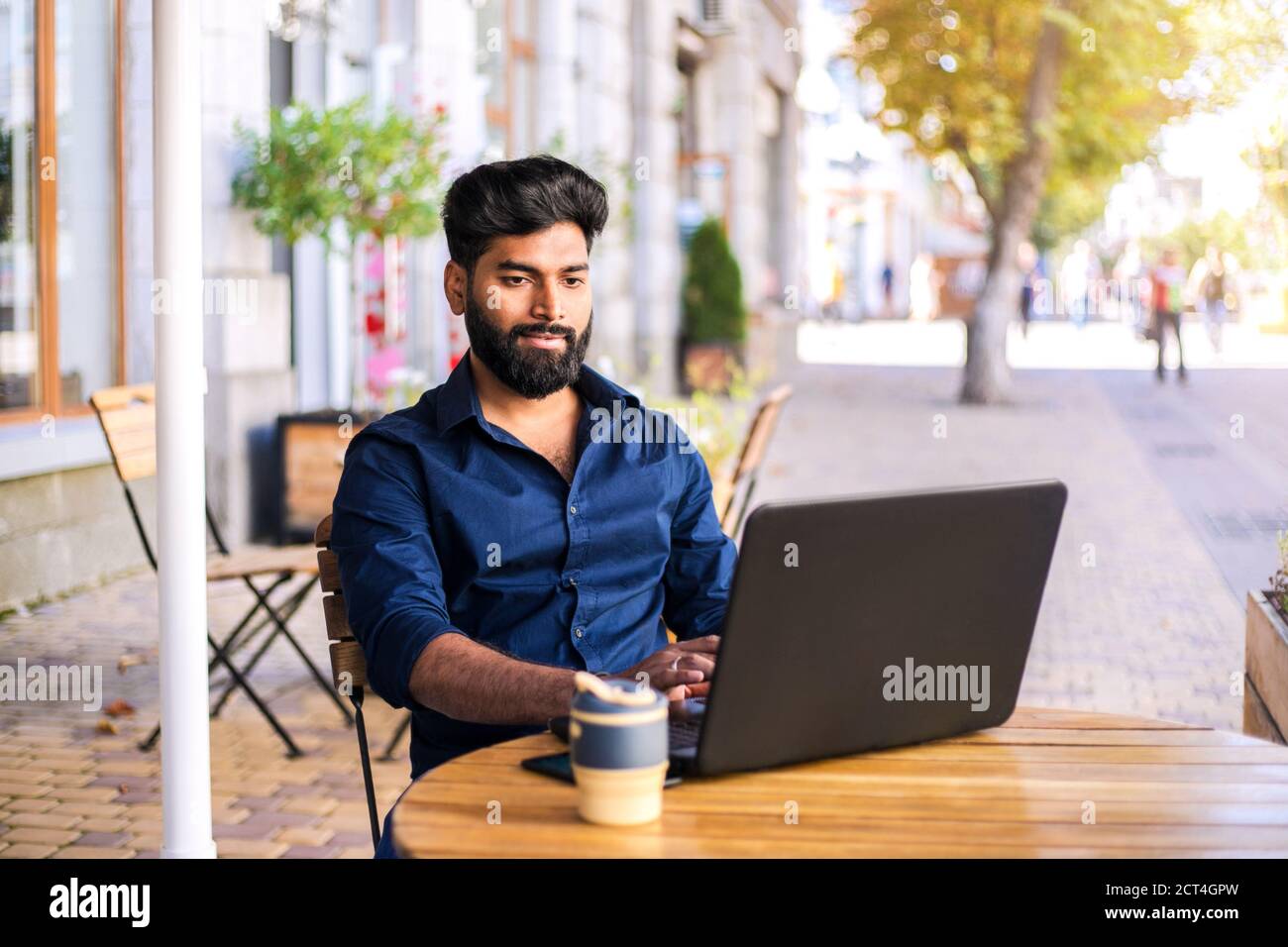 Junger erfolgreicher Geschäftsmann, der im Café im Freien arbeitet. Stockfoto