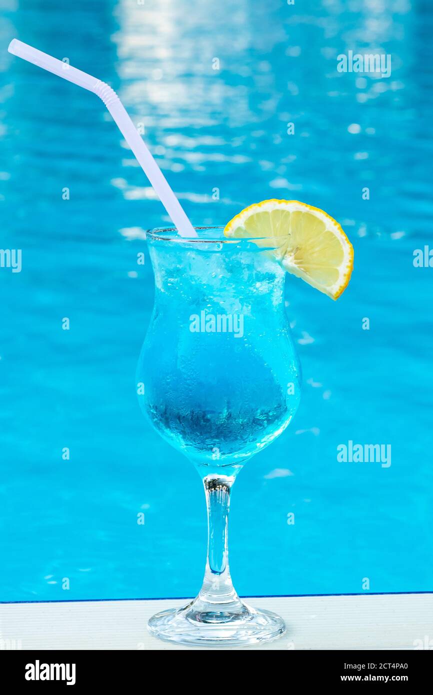 Blaue Lagune in einem Glas mit einem Stroh und einer Scheibe Zitrone. Süßer Cocktail im Sommer am Pool. Gemischtes alkoholisches Getränk. Strandparty, Urlaubskonzept. Wasser Stockfoto