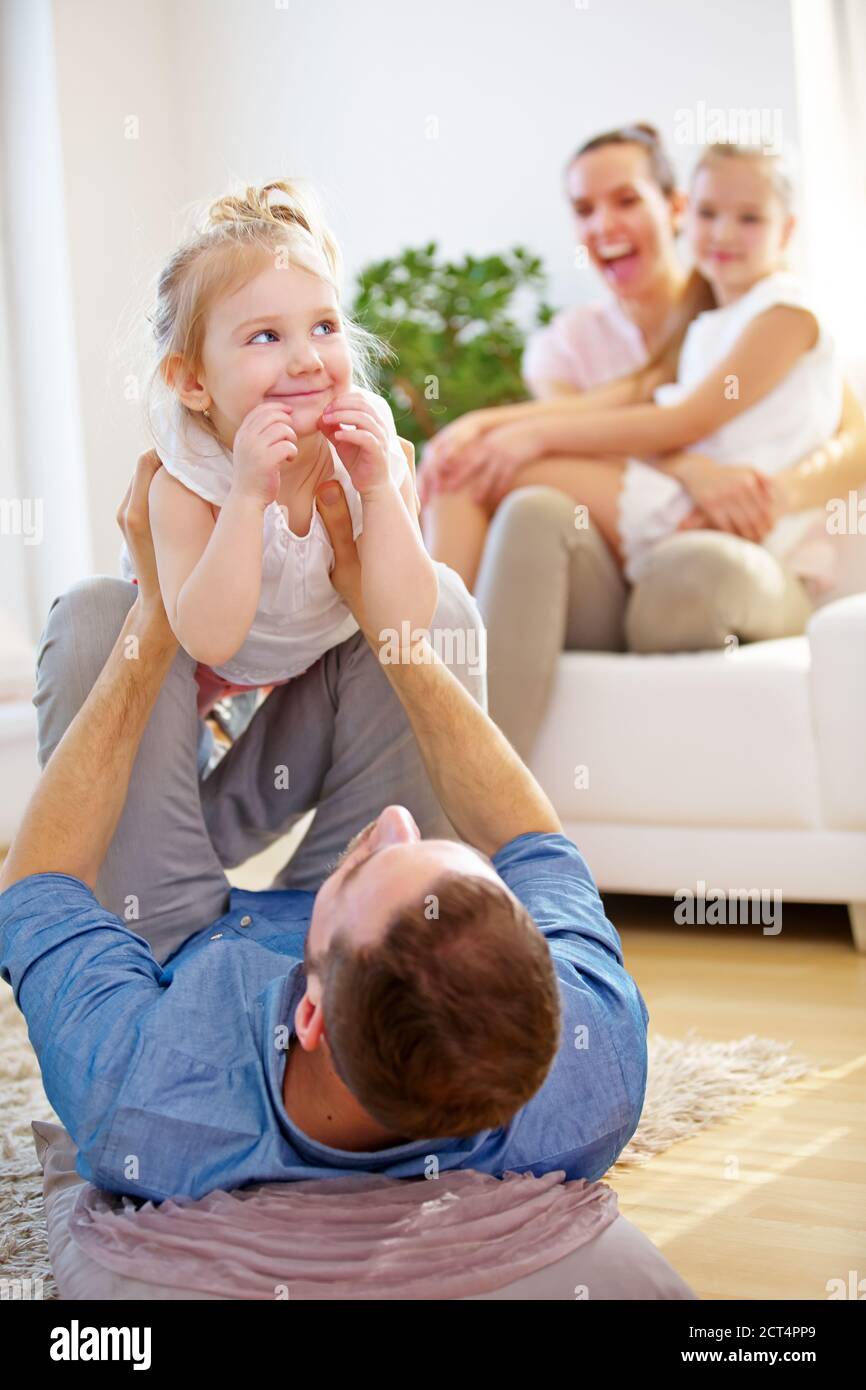 Glückliche Eltern spielen mit ihren beiden Kindern im Haus Stockfoto