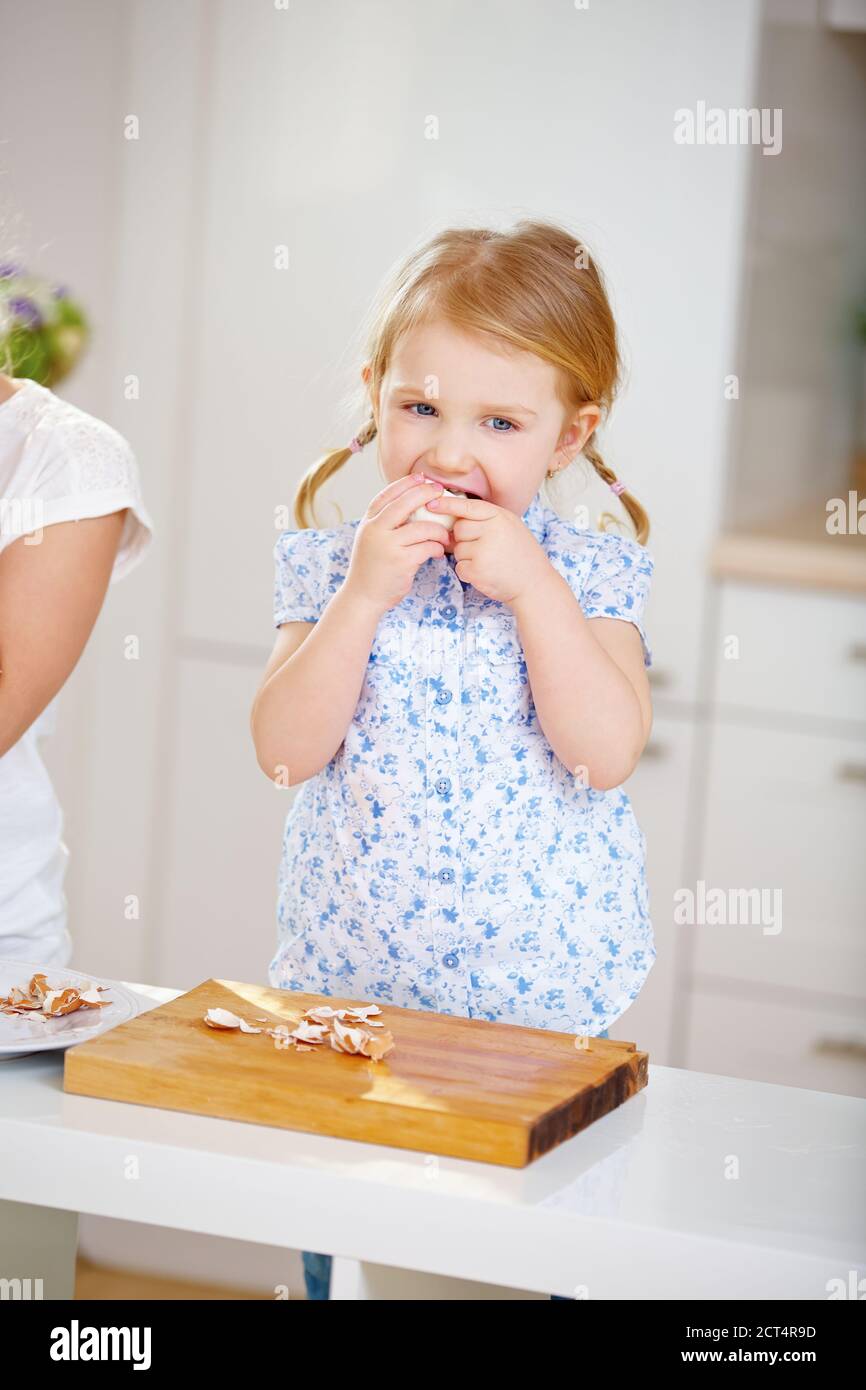 Kleines Kind isst ein Osterei in der Küche bei Ostern Stockfoto